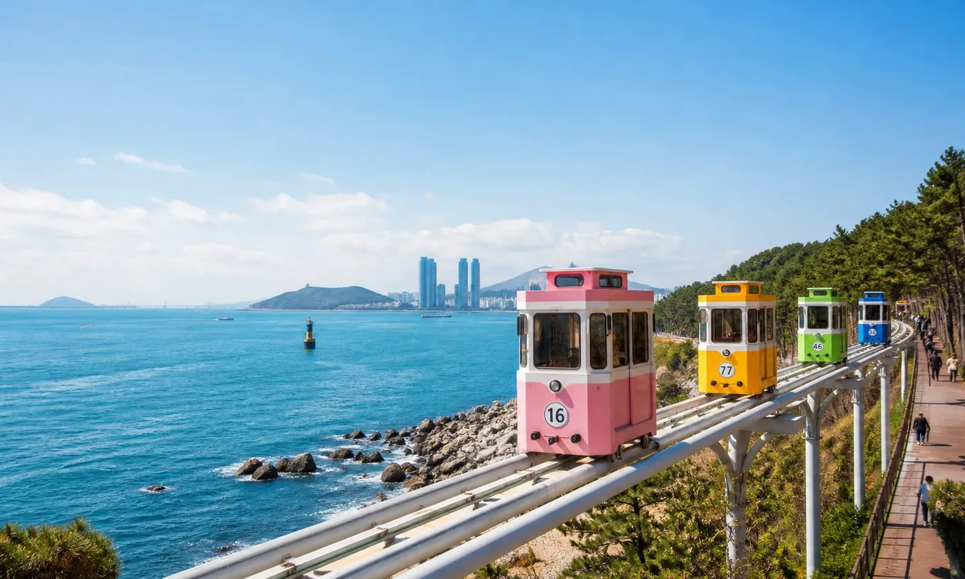 釜山海雲台藍線公園天空膠囊沿海行駛,粉彩車廂與碧海藍天,白天示意